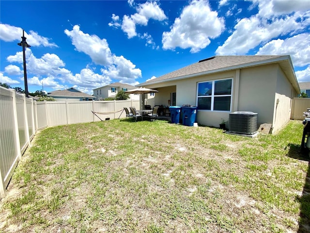 back of property with a lawn and central AC