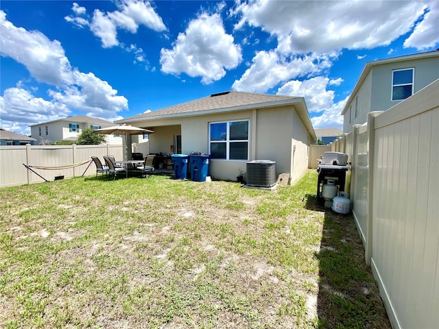 back of house with a yard and central AC unit