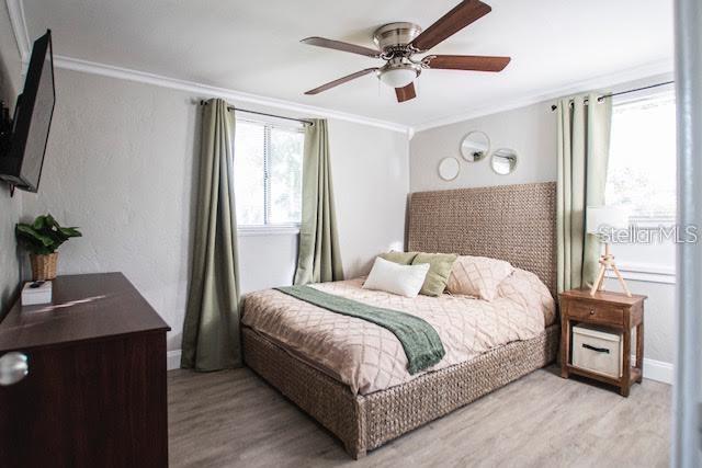 bedroom featuring ceiling fan, crown molding, and light hardwood / wood-style floors