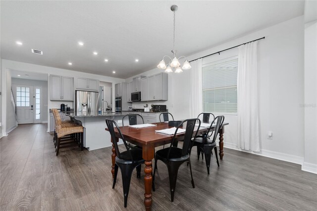 dining room featuring sink, a chandelier, and dark hardwood / wood-style flooring