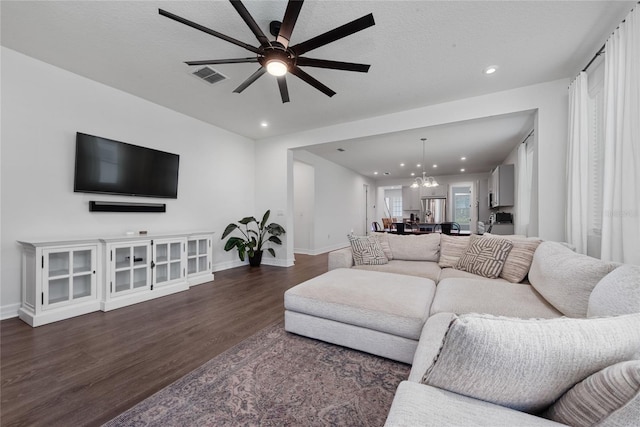 living room featuring dark wood-type flooring and ceiling fan with notable chandelier