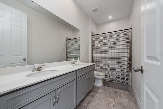 bathroom with double vanity, tile patterned flooring, and toilet