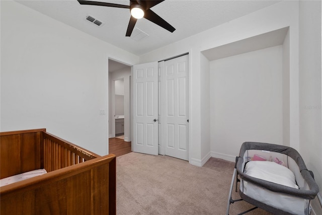 interior space with light carpet, ceiling fan, and a closet