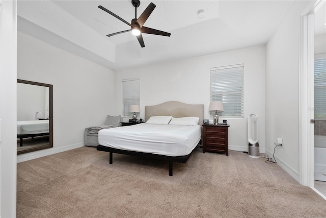 carpeted bedroom featuring ceiling fan and a raised ceiling