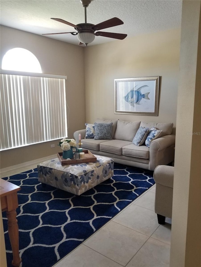 living room with tile flooring, ceiling fan, and a textured ceiling