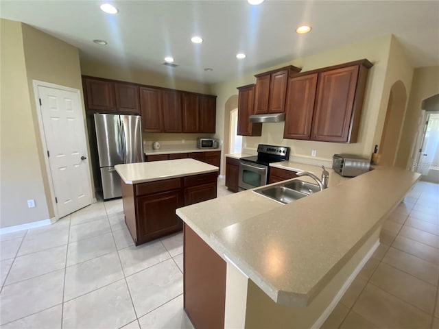 kitchen with kitchen peninsula, a kitchen island, light tile floors, sink, and appliances with stainless steel finishes