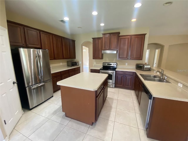 kitchen with kitchen peninsula, a center island, appliances with stainless steel finishes, sink, and light tile floors