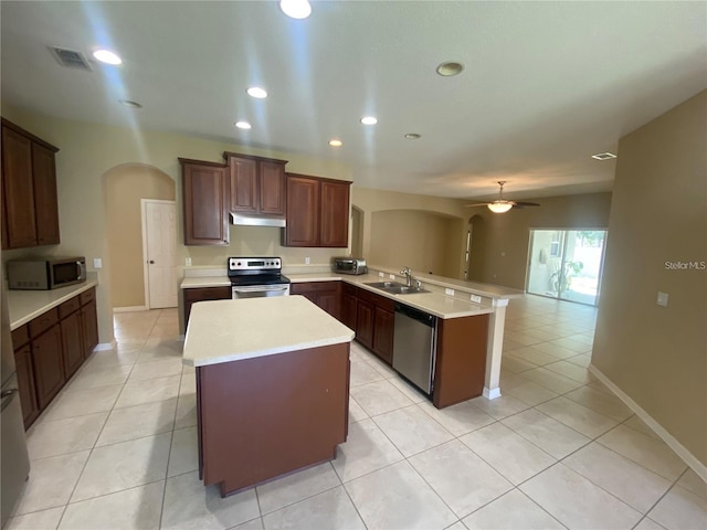 kitchen with appliances with stainless steel finishes, kitchen peninsula, light tile floors, and ceiling fan