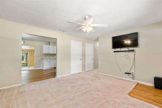 unfurnished living room featuring light colored carpet and ceiling fan