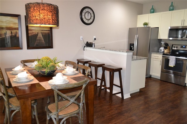 kitchen with white cabinetry, light stone counters, dark hardwood / wood-style flooring, and stainless steel appliances