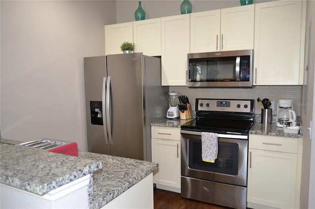 kitchen with dark wood-type flooring, white cabinetry, appliances with stainless steel finishes, light stone countertops, and decorative backsplash