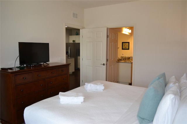 bedroom featuring ensuite bathroom and stainless steel fridge with ice dispenser