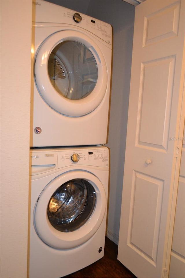 washroom featuring stacked washer / dryer and dark wood-type flooring