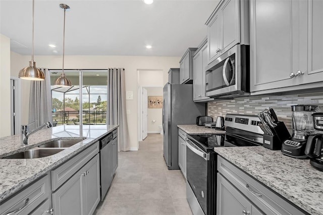 kitchen featuring sink, appliances with stainless steel finishes, gray cabinets, light stone countertops, and decorative backsplash