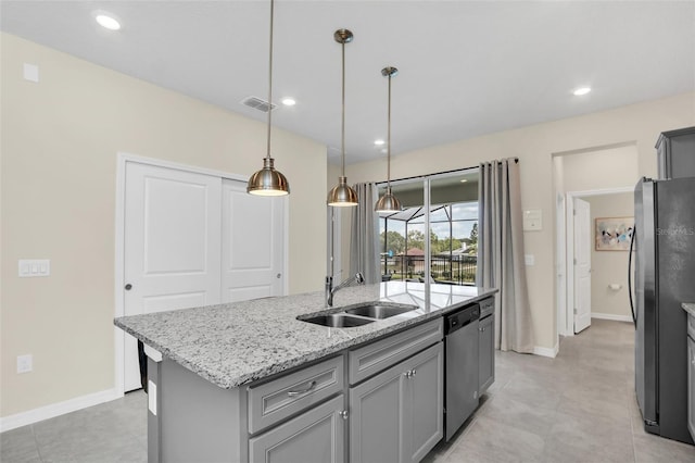 kitchen featuring pendant lighting, sink, stainless steel appliances, light stone countertops, and an island with sink