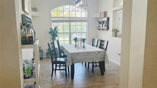 dining area featuring a towering ceiling, hardwood / wood-style floors, and a chandelier