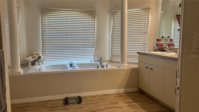 bathroom featuring a bath to relax in, vanity, and decorative columns