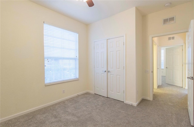 unfurnished bedroom with ceiling fan, light carpet, and a closet