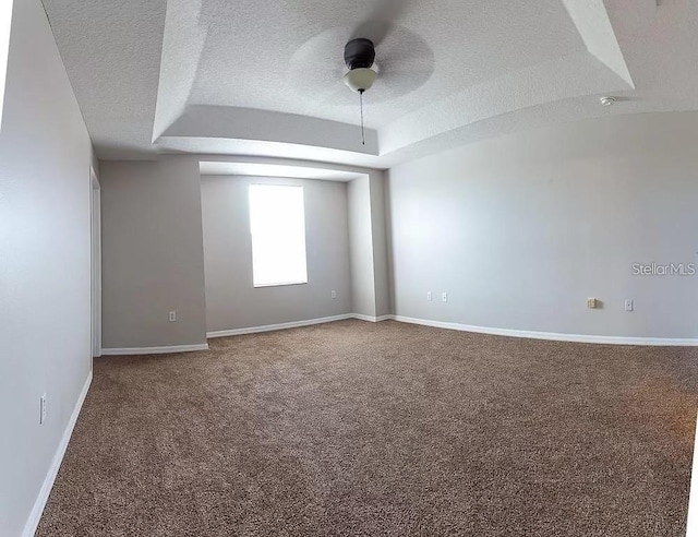 spare room with carpet flooring, ceiling fan, a textured ceiling, and a raised ceiling