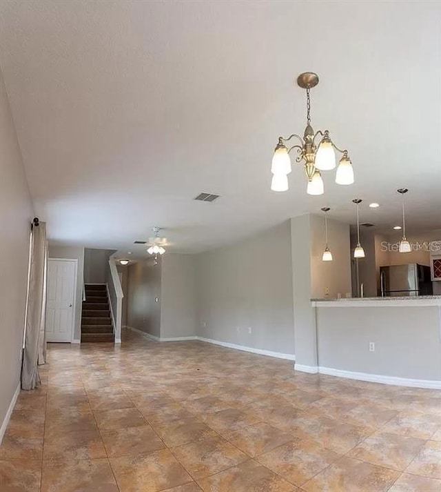 tiled spare room featuring ceiling fan with notable chandelier