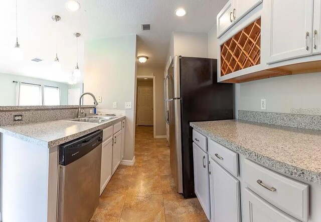 kitchen with stainless steel appliances, pendant lighting, light tile floors, sink, and white cabinets