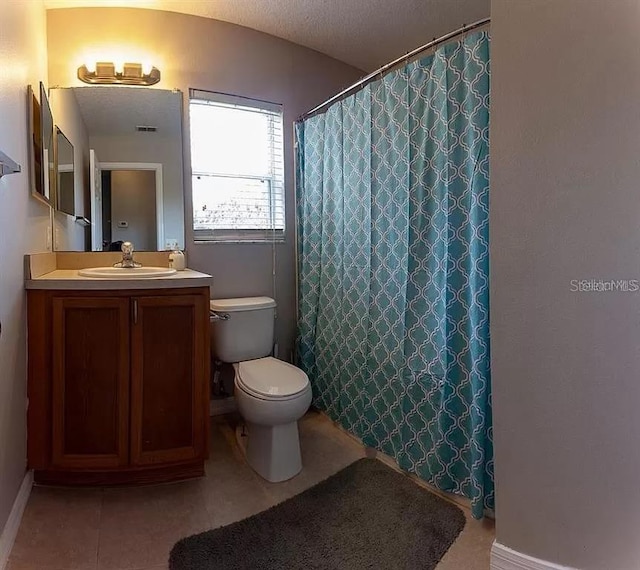 bathroom featuring tile floors, a textured ceiling, toilet, and vanity