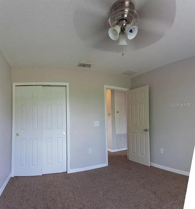 unfurnished bedroom with a closet, dark colored carpet, and ceiling fan