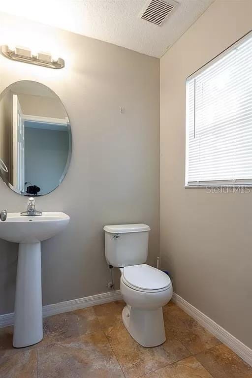 bathroom featuring tile floors, a textured ceiling, and toilet