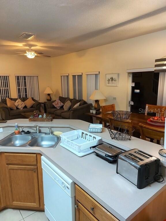 kitchen with ceiling fan, a textured ceiling, white dishwasher, sink, and light tile floors