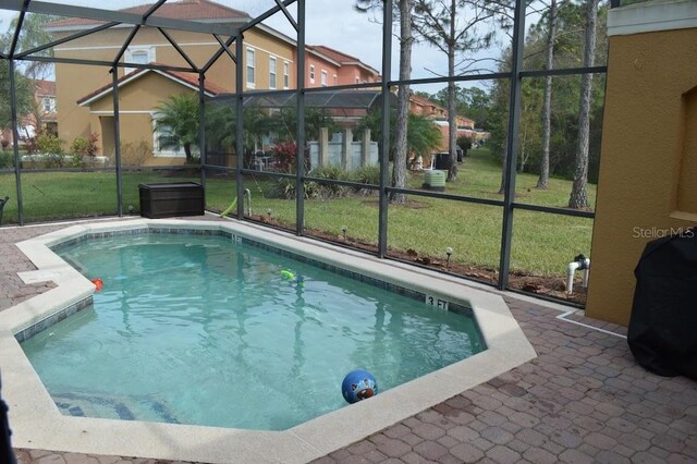 view of swimming pool featuring glass enclosure, a patio area, and a lawn