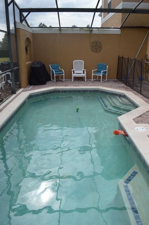 view of swimming pool featuring glass enclosure