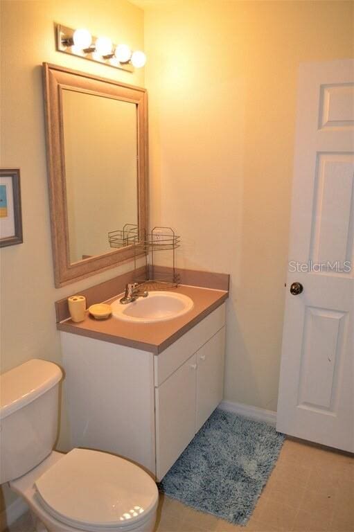 bathroom with tile flooring, vanity, and toilet