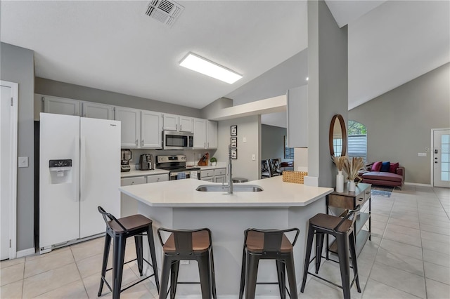 kitchen with white cabinetry, sink, stainless steel appliances, vaulted ceiling, and a breakfast bar area