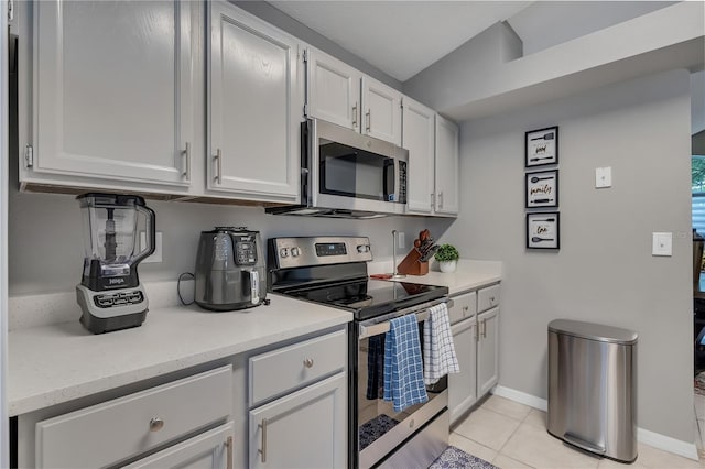 kitchen featuring light tile patterned flooring, white cabinets, stainless steel appliances, and vaulted ceiling