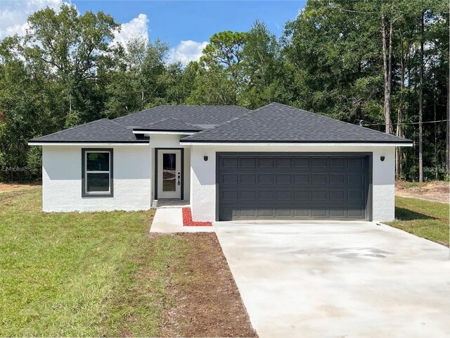 view of front of property with stucco siding, a shingled roof, concrete driveway, an attached garage, and a front yard