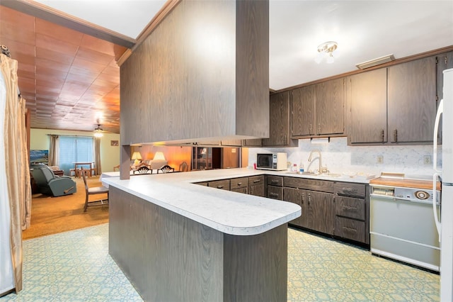 kitchen featuring white appliances, a sink, a peninsula, and light floors