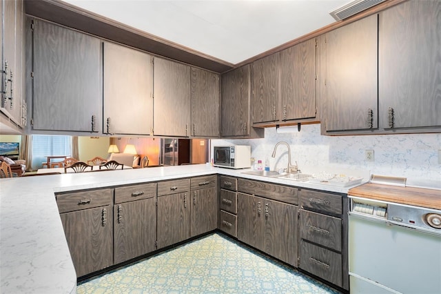 kitchen featuring light floors, light countertops, visible vents, a sink, and dishwasher