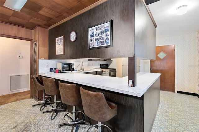 kitchen featuring light countertops, visible vents, ornamental molding, black appliances, and wallpapered walls