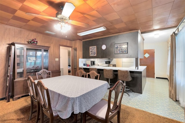 dining area with light floors, ceiling fan, and wallpapered walls