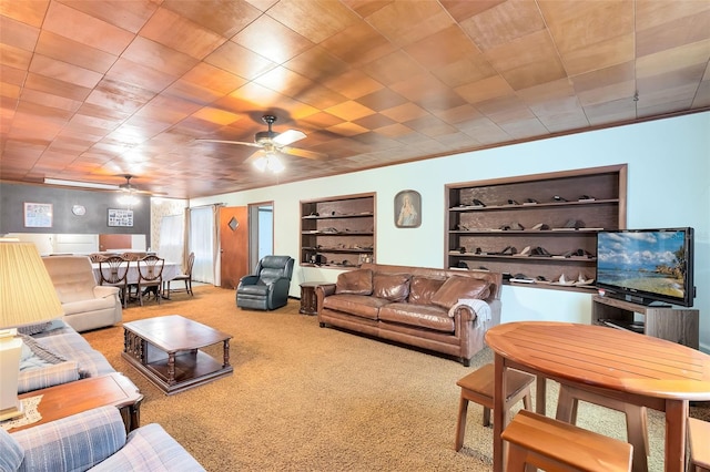 living room with ceiling fan, carpet floors, and built in shelves