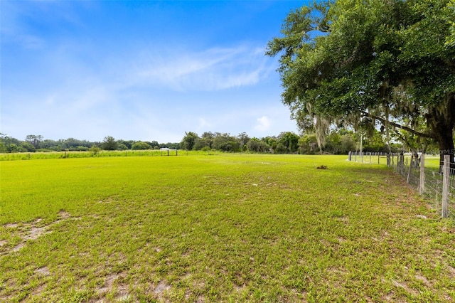 view of yard with fence and a rural view