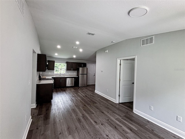 kitchen with appliances with stainless steel finishes, dark brown cabinets, sink, and dark wood-type flooring