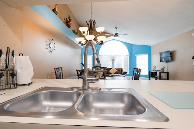 kitchen featuring ceiling fan with notable chandelier, vaulted ceiling, decorative light fixtures, and sink