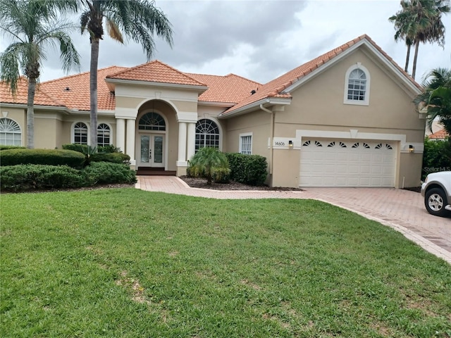 mediterranean / spanish-style home with french doors, a garage, and a front lawn