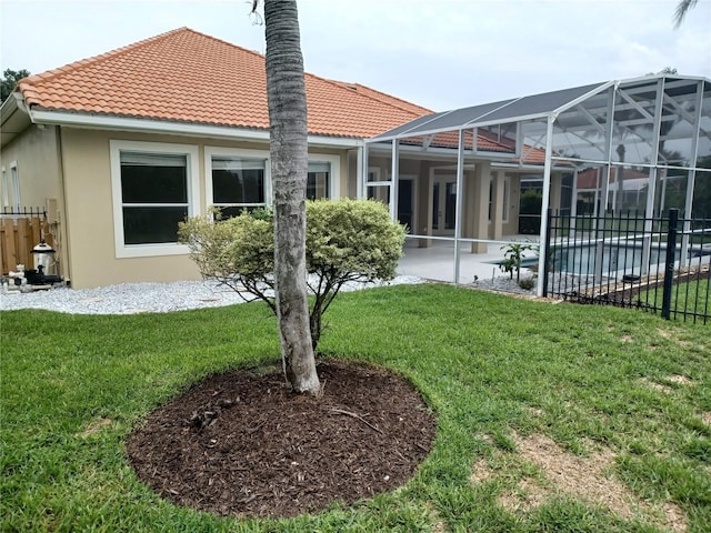 back of house with a patio, glass enclosure, and a lawn