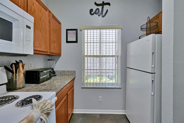 kitchen with white appliances and dark tile patterned floors