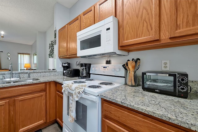 kitchen with sink, white appliances, light tile patterned floors, light stone counters, and a textured ceiling