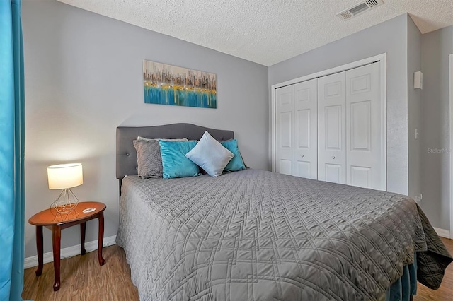 bedroom featuring hardwood / wood-style floors, a closet, and a textured ceiling