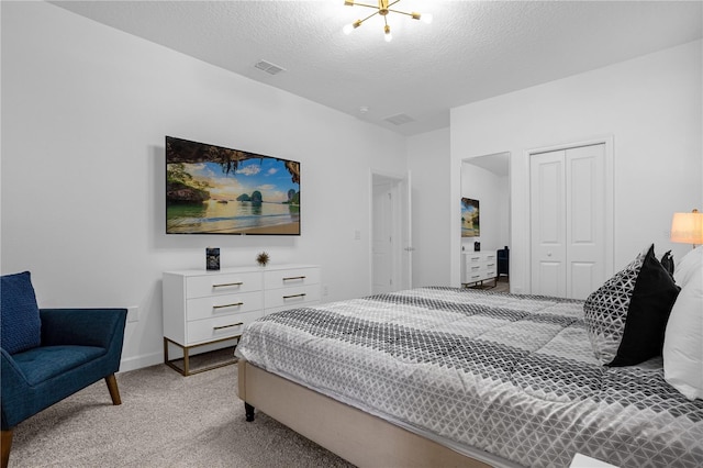 carpeted bedroom featuring a textured ceiling, a closet, and a notable chandelier