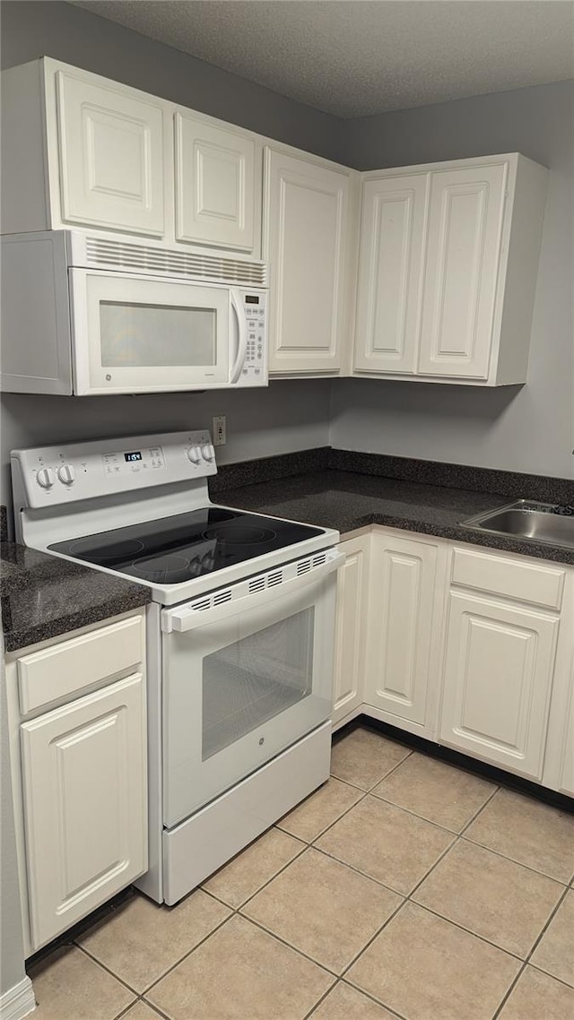 kitchen with white cabinetry, white appliances, and light tile patterned floors